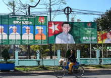 Foto ini, yang diambil pada 9 Desember 2025, menunjukkan seorang wanita melewati papan reklame kampanye menjelang pemilihan umum Myanmar di Pyin Oo Lwin, Wilayah Mandalay, Myanmar/ AFP